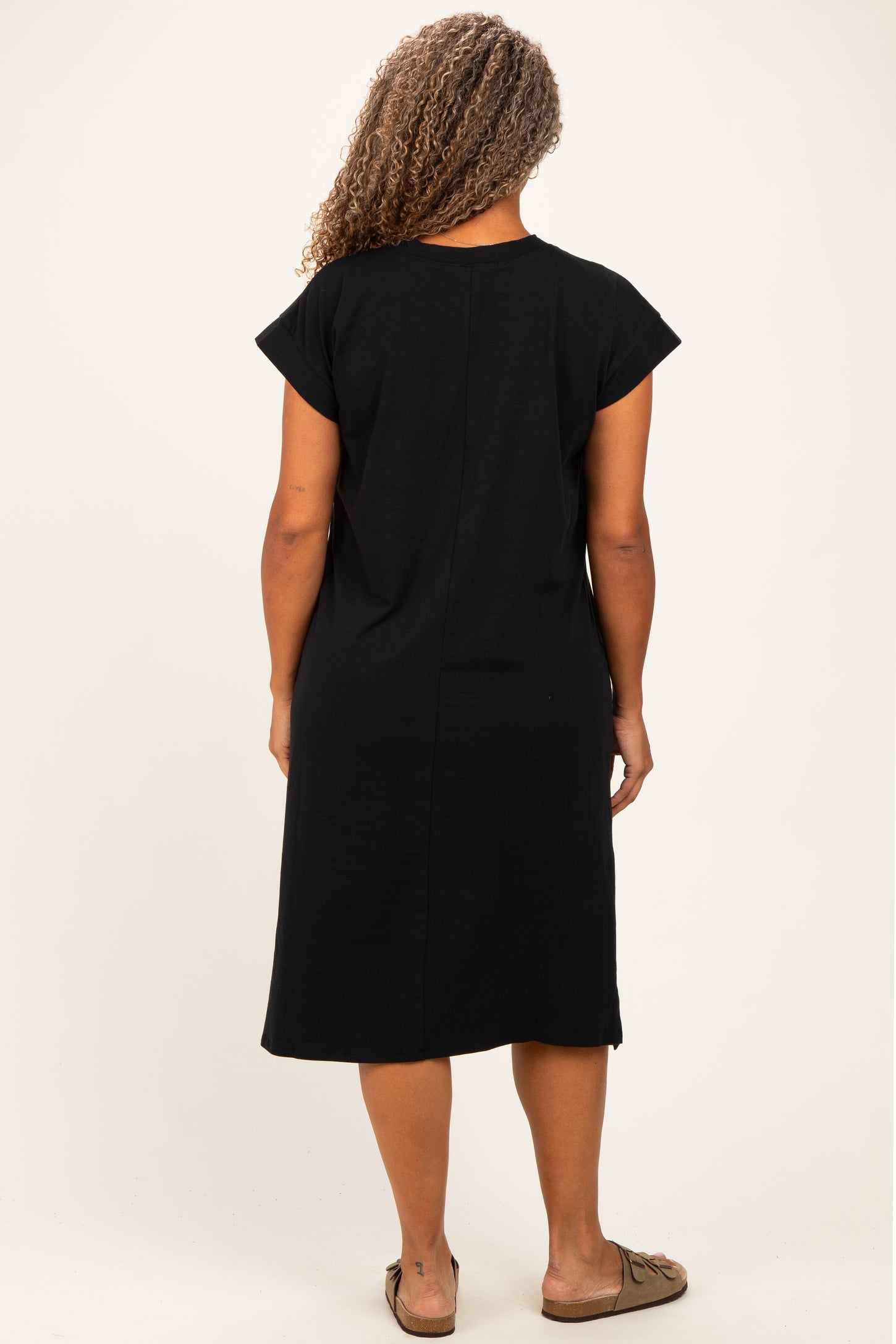 woman wearing a black short sleeve plus size dress with a relaxed fit, view from the back