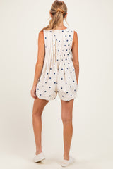 woman wearing a polka dot white maternity romper, showing a relaxed fit and pleated back design