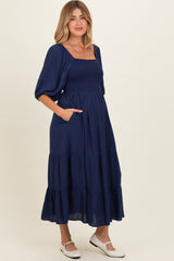woman wearing a navy blue maternity maxi dress with puff sleeves and pockets