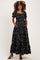 woman wearing a black floral print maternity maxi dress with puff sleeves and pockets