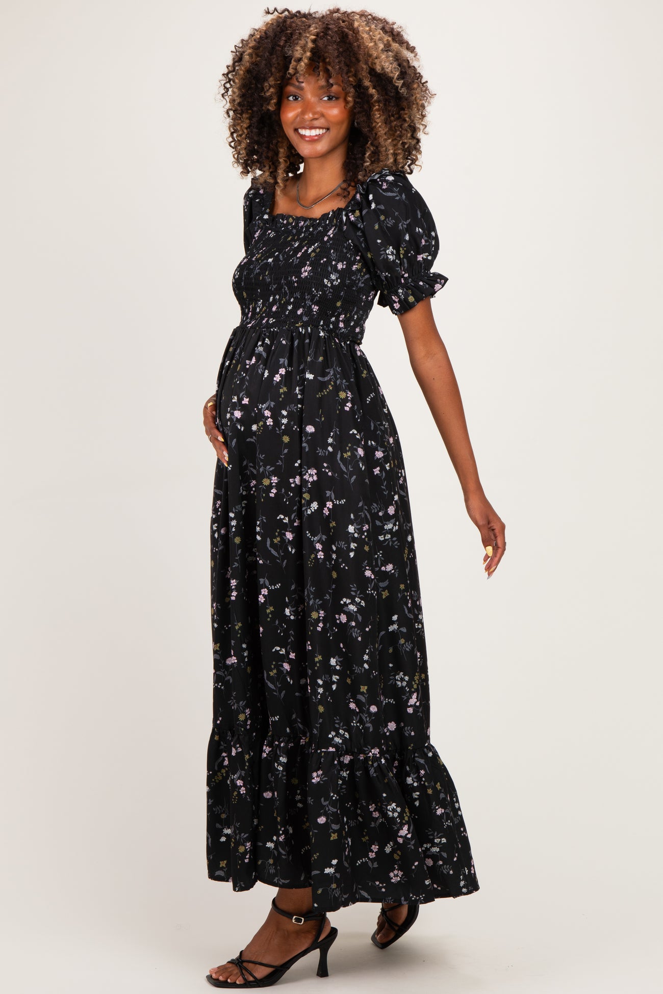 woman wearing a black floral maternity maxi dress with puff sleeves and a visible baby bump