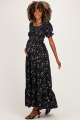 woman wearing a black floral maternity maxi dress with puff sleeves and a visible baby bump