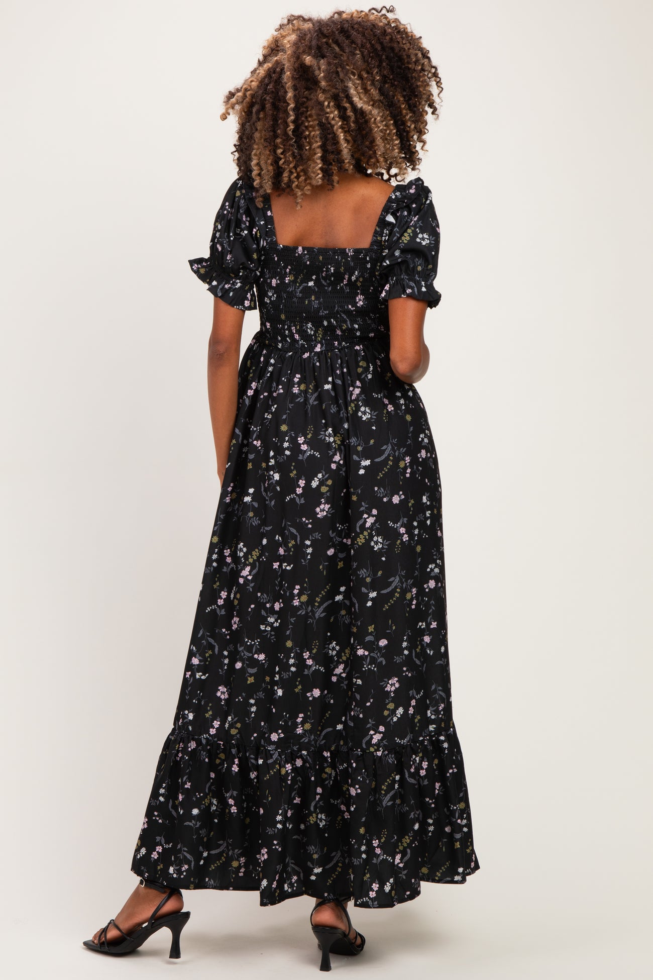 woman wearing a black floral maternity maxi dress with short puff sleeves and a smocked bodice, showing her baby bump