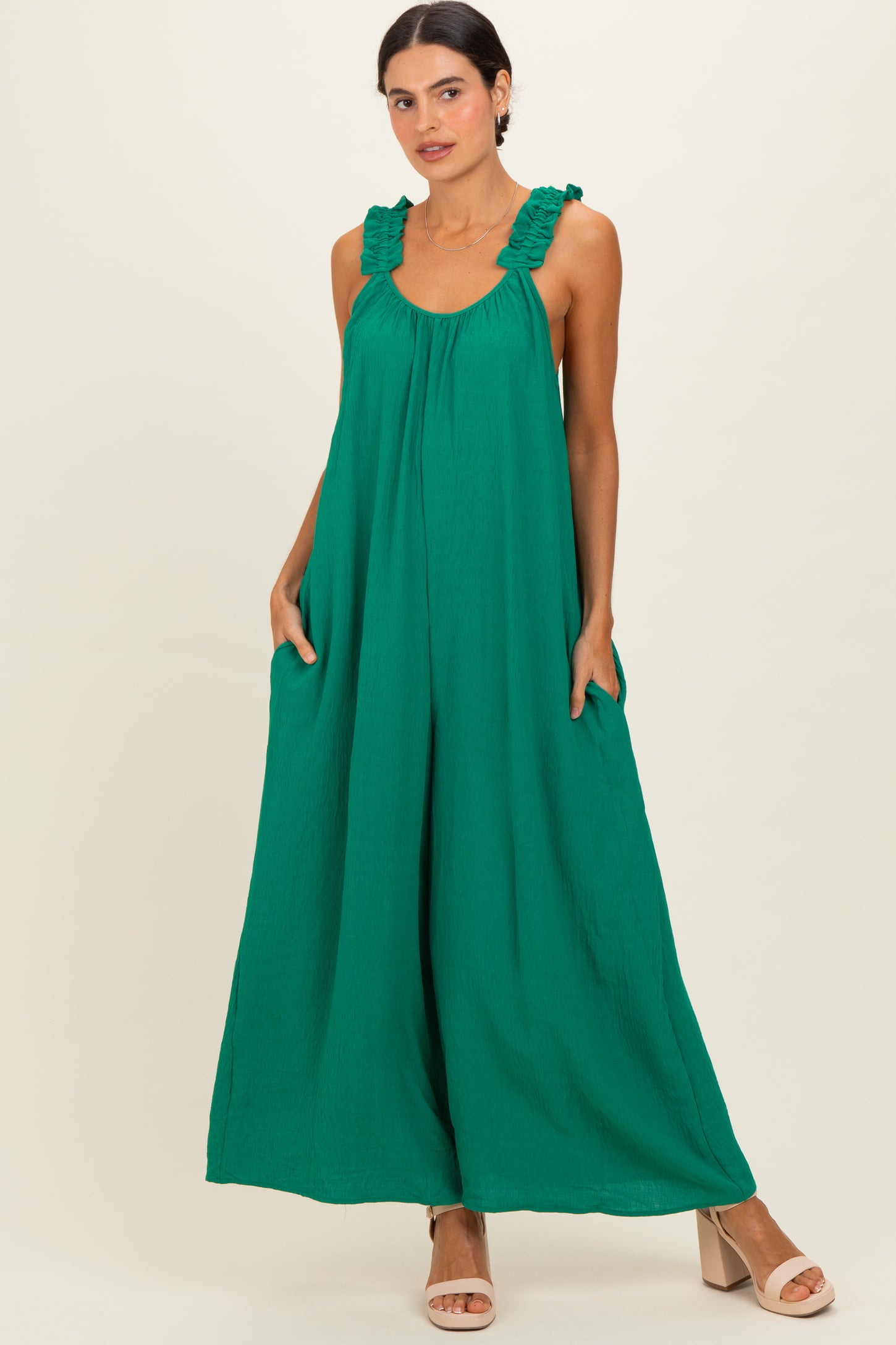 woman wearing a green sleeveless maxi dress with ruffled straps and pockets