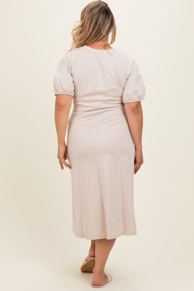 woman wearing a light beige maternity plus dress with puff sleeves, standing with her back to the camera