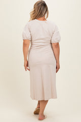 woman wearing a light beige maternity plus dress with puff sleeves, standing with her back to the camera
