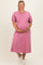 woman wearing a pink puff sleeve maternity dress and gently holding her baby bump