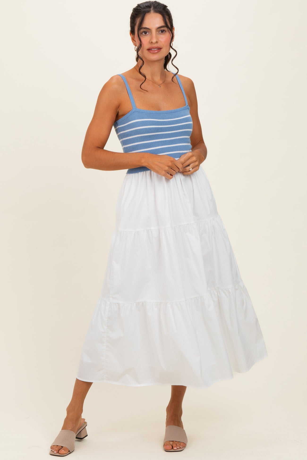 woman wearing a blue and white striped crop top and a flowy white tiered maxi skirt