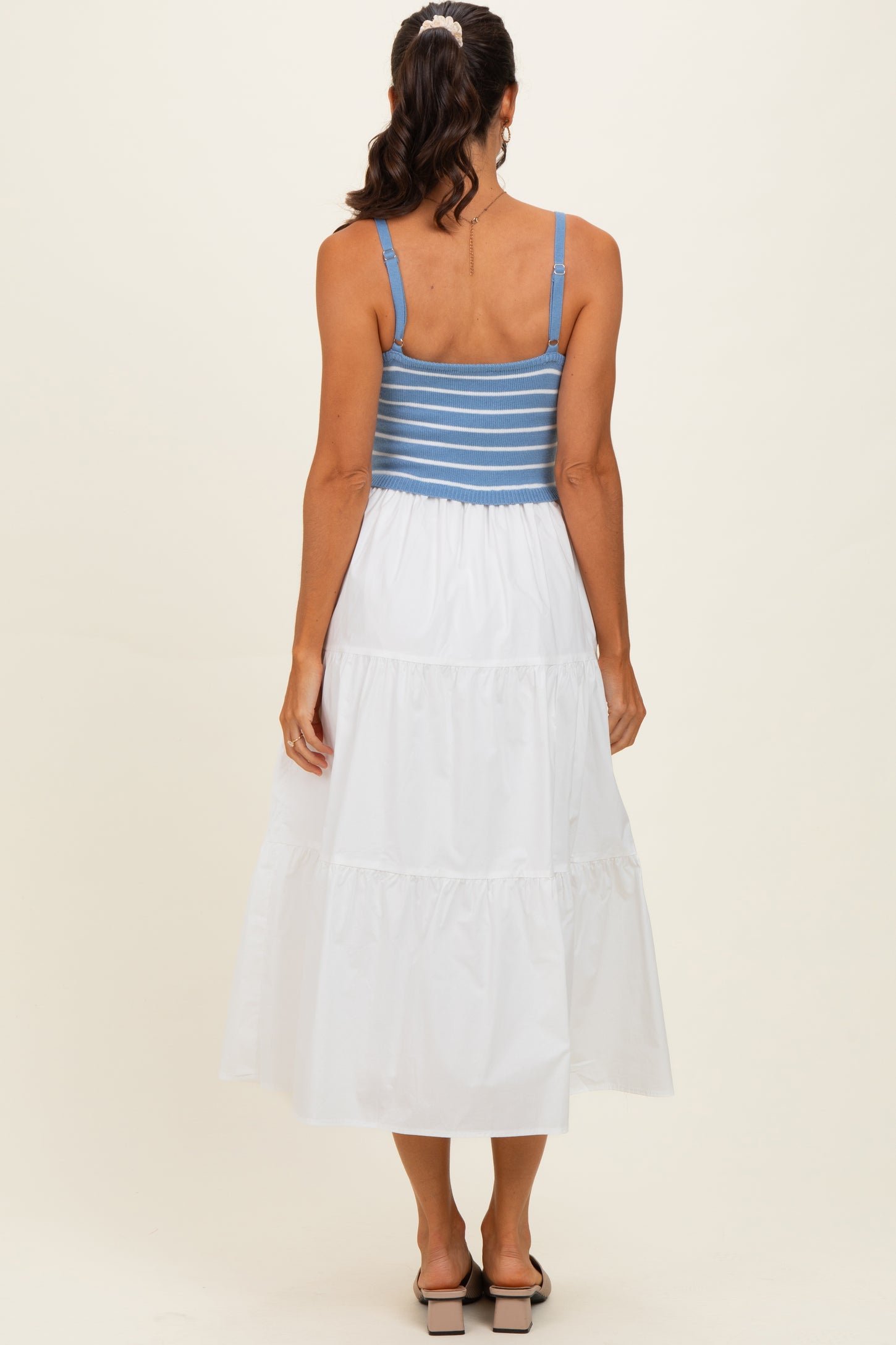 woman wearing a blue and white striped backless maxi dress with a tiered white skirt and a fitted bodice