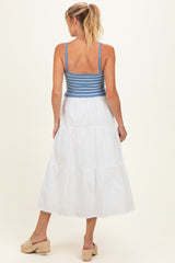 woman wearing a maternity sleeveless white tiered dress with a blue striped bodice, showing her back and a casual hairstyle
