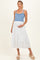 woman wearing a blue striped maternity tank top and a white tiered maxi skirt, holding her baby bump