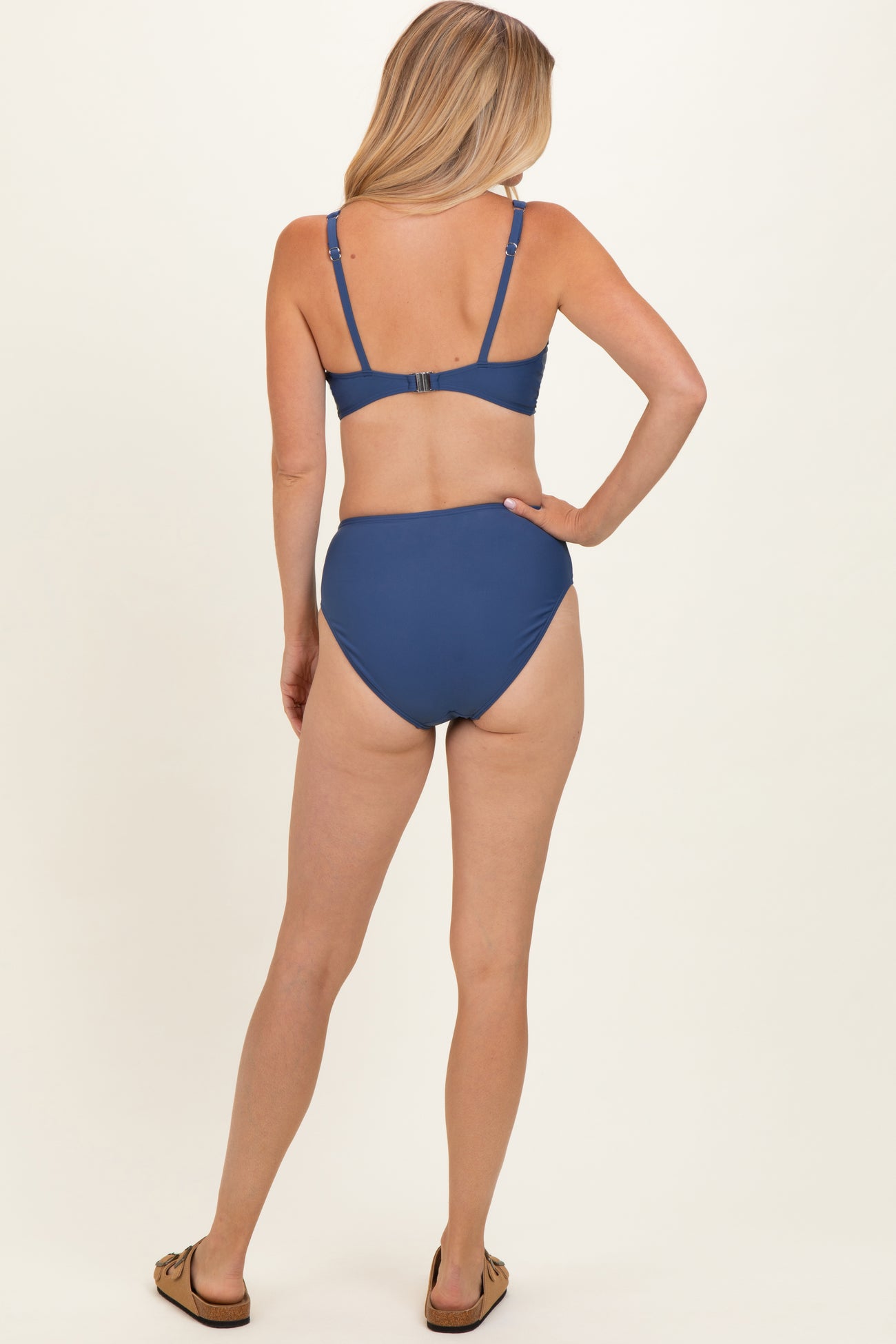woman wearing a blue bikini set with a bralette top and high-waisted bottom, viewed from the back