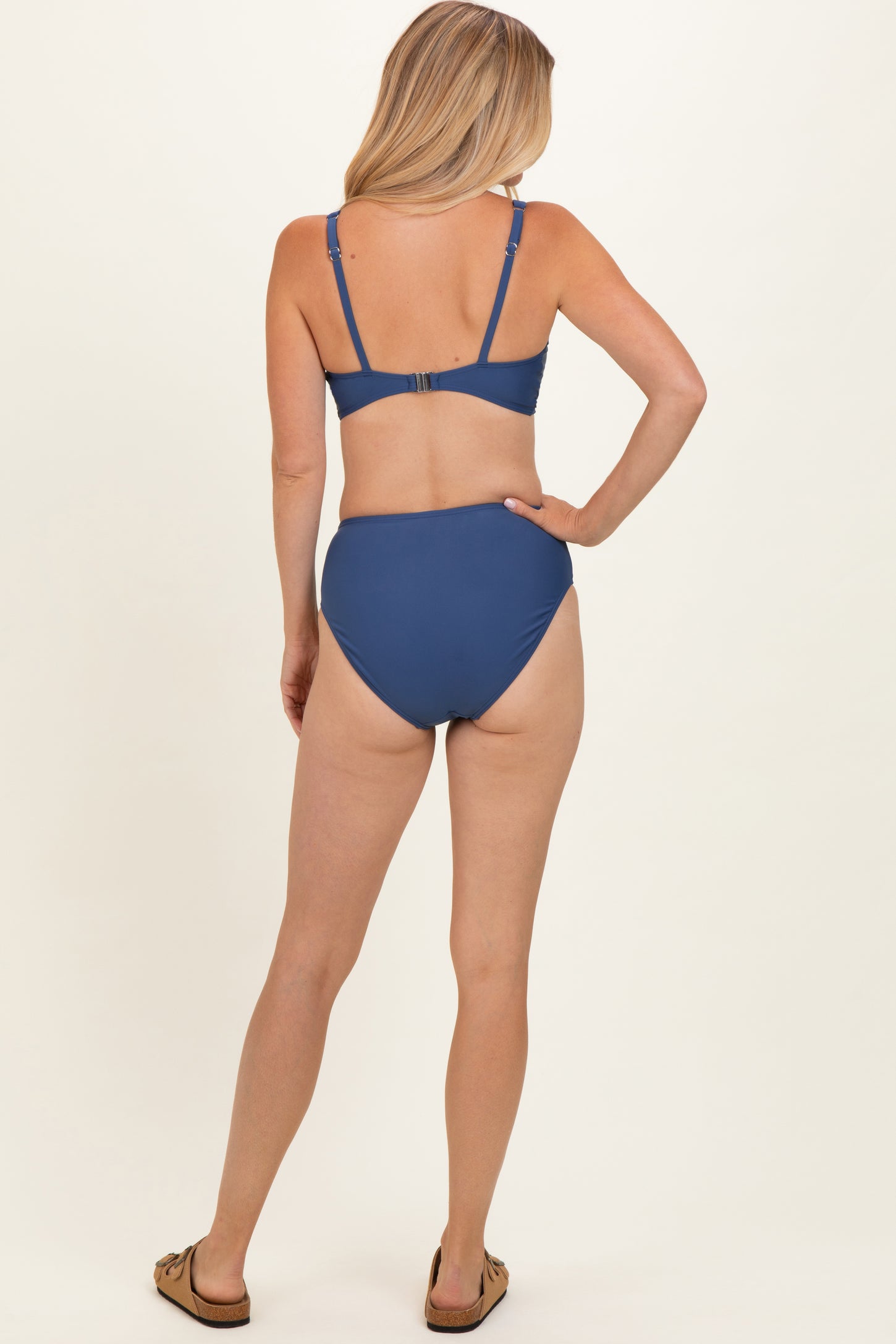 woman wearing a blue bikini set with a bralette top and high-waisted bottom, viewed from the back