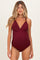 woman wearing a burgundy maternity swimsuit with a plunging neckline and adjustable straps, showcasing her baby bump