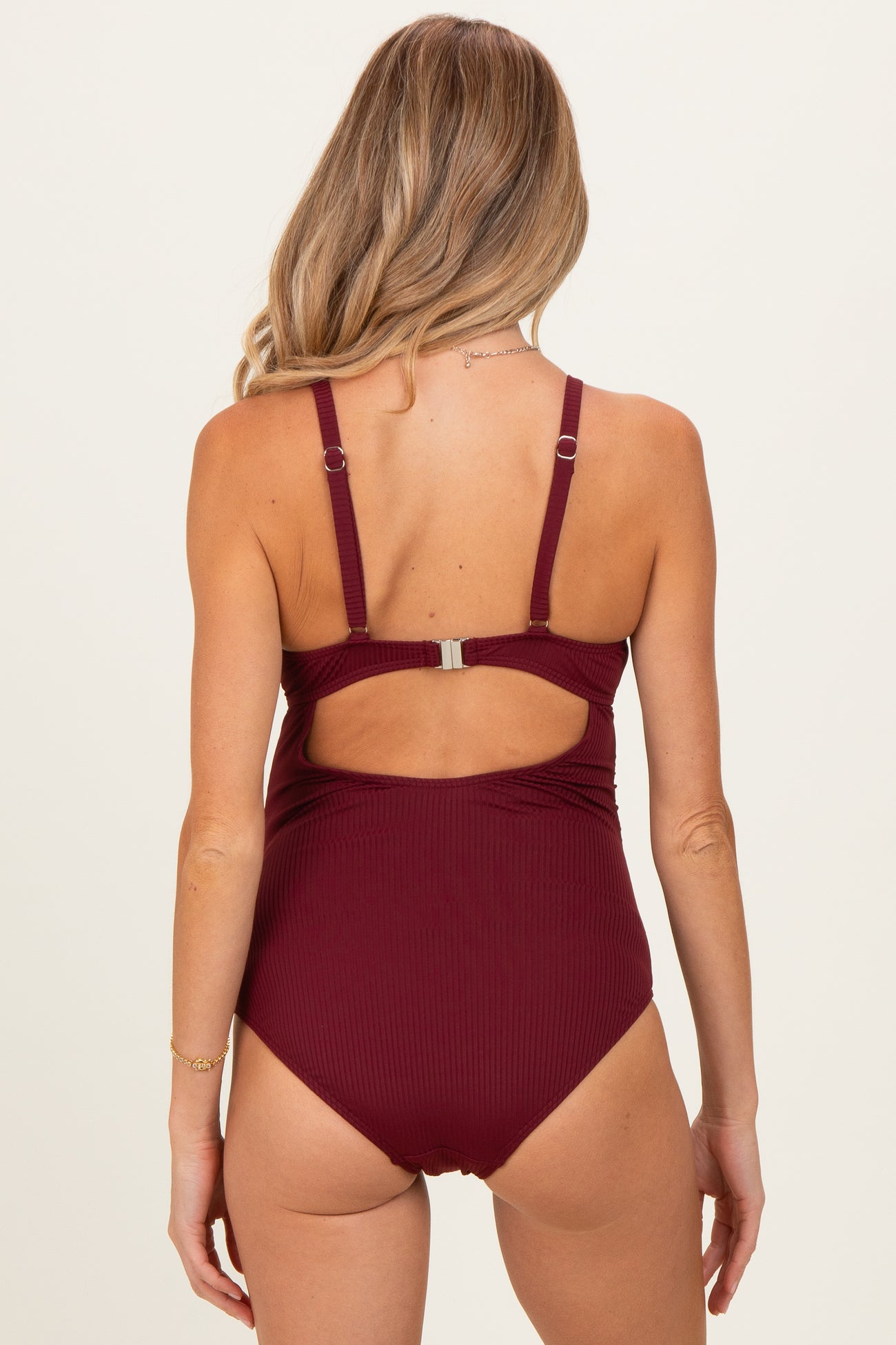 woman wearing a burgundy maternity swimsuit with adjustable straps and a cutout back design