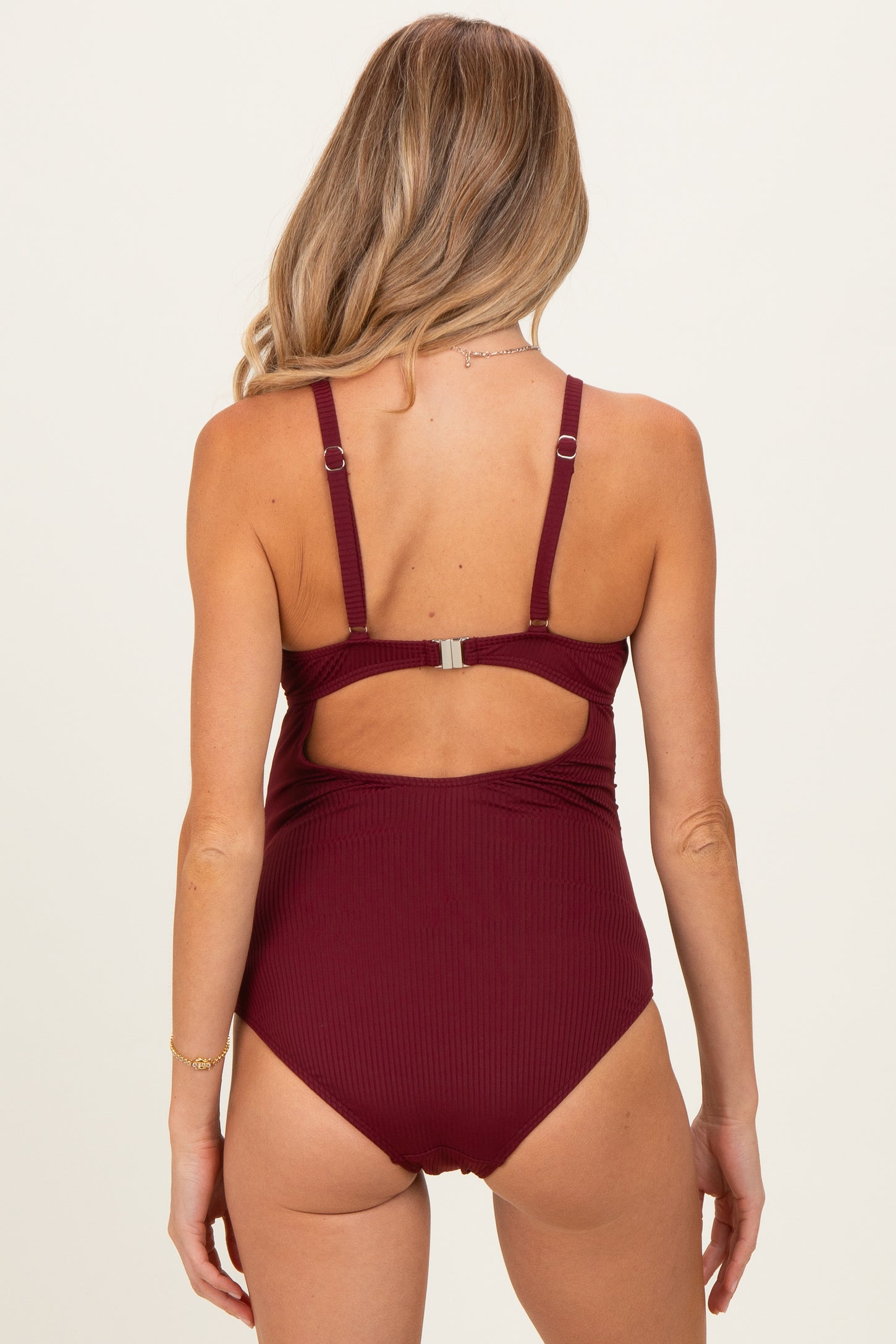 woman wearing a burgundy maternity swimsuit with adjustable straps and a cutout back design