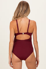 woman wearing a burgundy maternity swimsuit with adjustable straps and a cutout back design