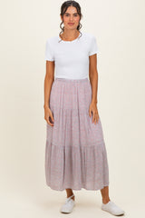 woman wearing a white short sleeve top and a pink floral tiered maxi skirt with white sneakers