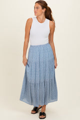 woman wearing a white sleeveless ribbed top and a blue floral tiered maxi skirt