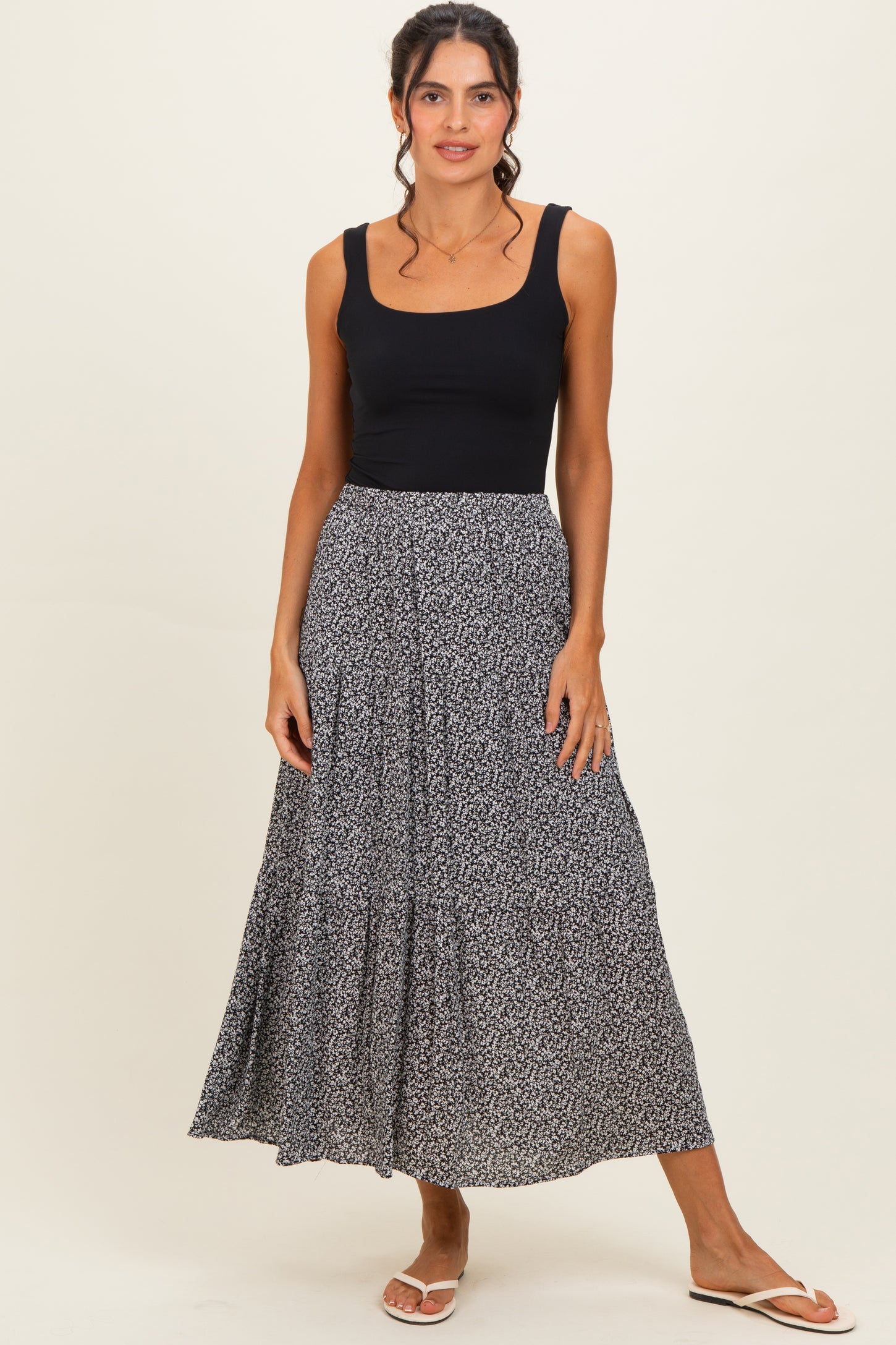 woman wearing a black sleeveless top and a flowy black and white patterned maxi skirt