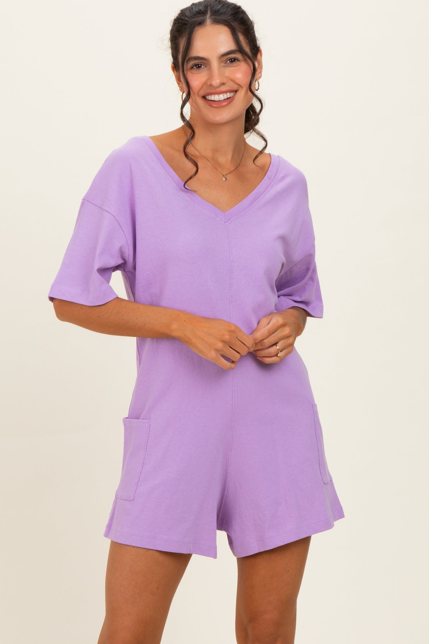 woman wearing a lavender short-sleeve v-neck romper with front pockets