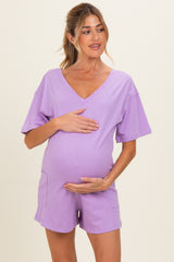 woman wearing a lavender maternity romper and holding her baby bump