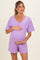 woman wearing a lavender maternity romper and holding her baby bump