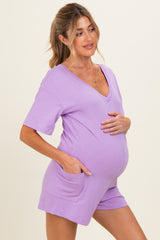 woman wearing a lavender short sleeve maternity romper, showing her baby bump with pockets on the sides