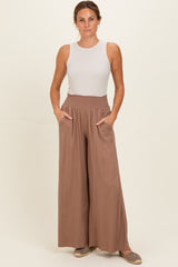woman wearing a tan wide-leg pant with pockets and a white sleeveless top