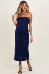 woman wearing a navy strapless maternity dress with floral cutout details and a visible baby bump