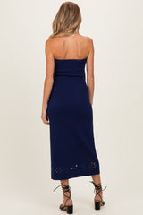 woman wearing a navy blue strapless maternity dress with floral cutout details at the hem