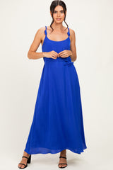 woman wearing a vibrant blue maxi dress with ruffled straps and a tie waist detail