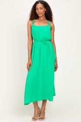 woman wearing a green maxi dress with spaghetti straps and a bow accent at the waist
