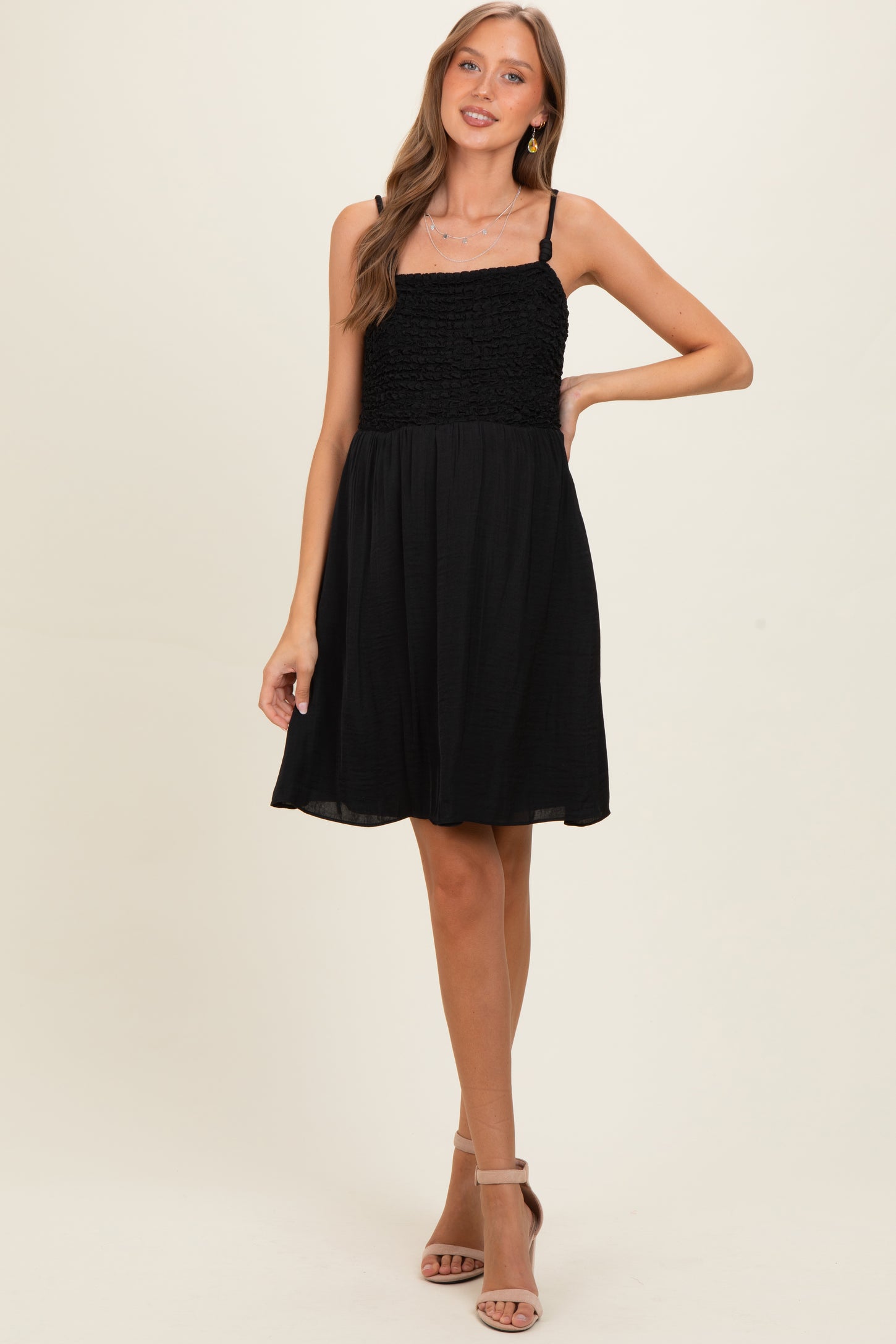 woman wearing a black maternity dress with a smocked bodice and spaghetti straps, no baby bump visible