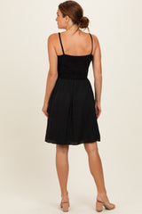 woman wearing a black sundress with a smocked bodice and flared skirt, shown from the back