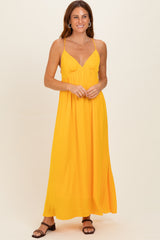 woman wearing a bright yellow maxi dress with a v-neckline and thin straps, standing confidently