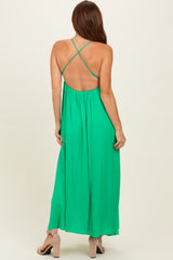 woman wearing a green backless maxi dress with cross-strap detailing and a flowing silhouette