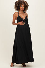 woman wearing a black halter maternity maxi dress and gently holding her baby bump
