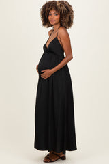 woman wearing a black maternity maxi dress with a deep V-neck and holding her baby bump
