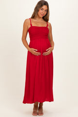 woman wearing a red maternity maxi dress with a smocked bodice, holding her baby bump