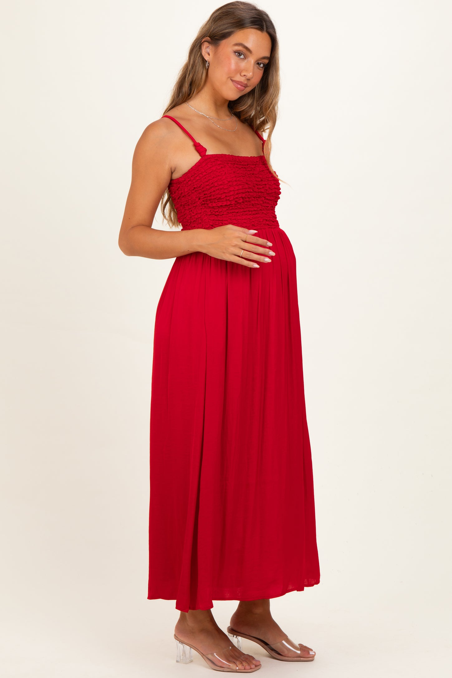 woman wearing a red maternity dress with smocked bodice, holding her baby bump