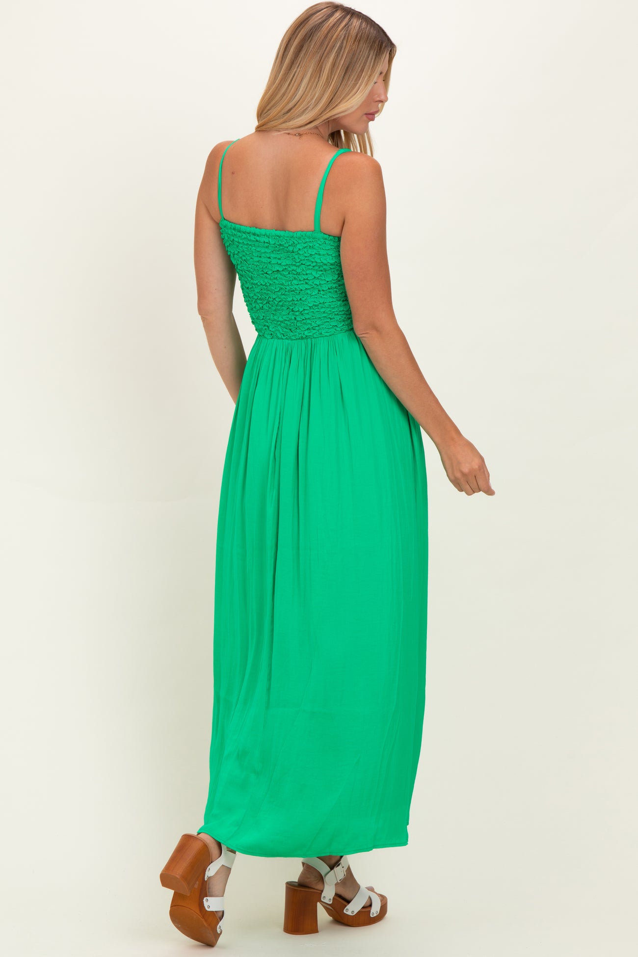 woman wearing a bright green maxi dress with a smocked bodice and adjustable straps, viewed from the back