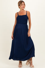 woman wearing a navy blue maternity maxi dress with smocked bodice and spaghetti straps, showcasing her baby bump