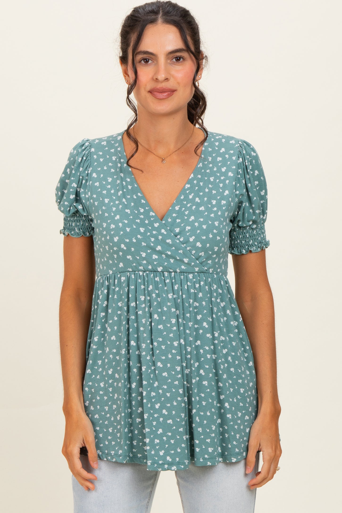 woman wearing a teal floral print short sleeve wrap top with puff sleeves and a gathered waist