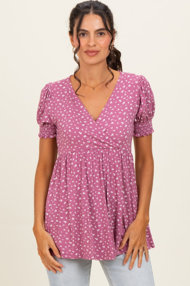 woman wearing a pink puff sleeve top with white floral prints and a v-neckline, paired with light blue jeans