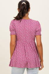 woman wearing a purple short sleeve peplum top with a floral pattern and smocked details on the sleeves