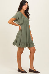 woman wearing an olive green short sleeve dress with a ruffled hem and a fitted bodice