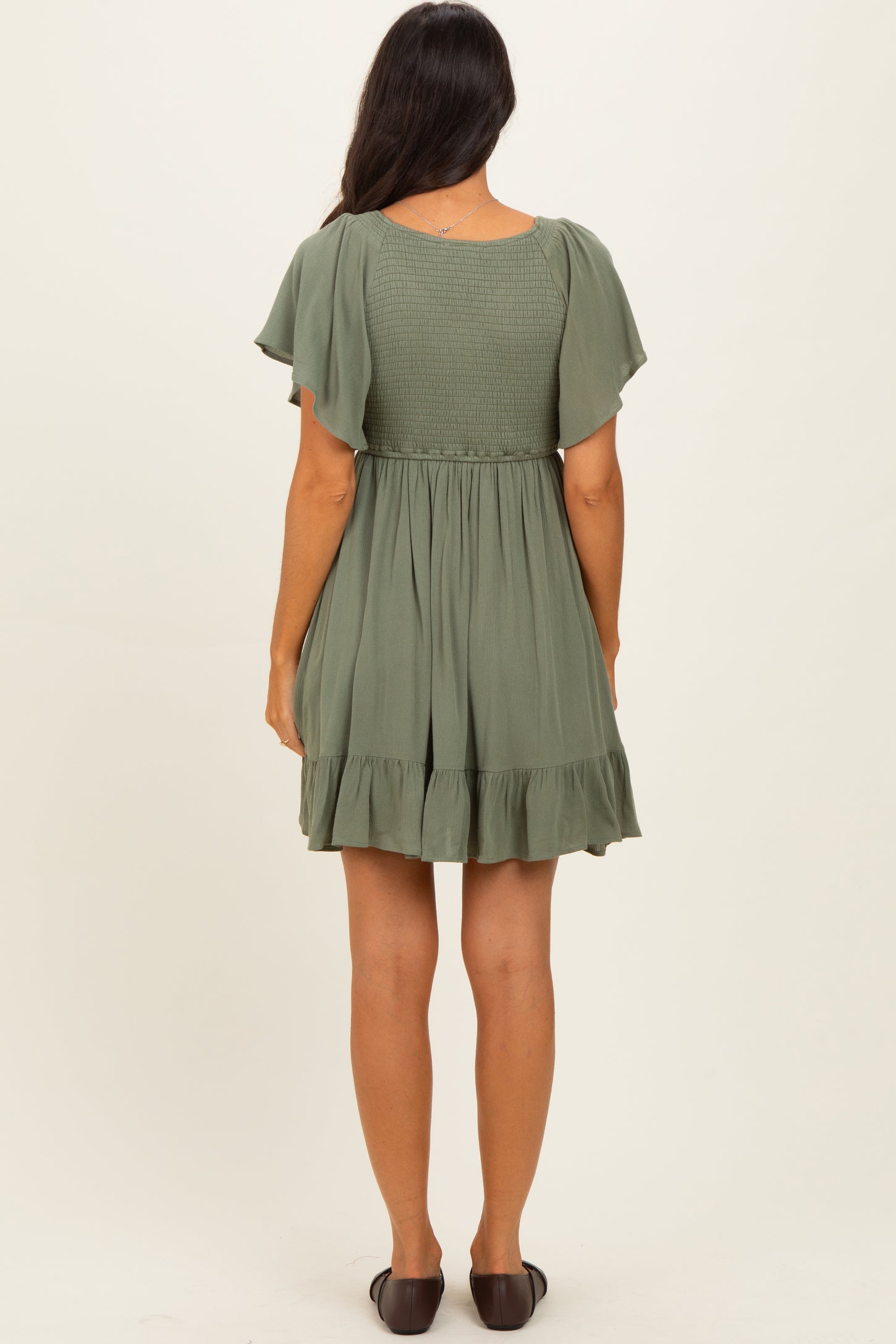 woman wearing an olive green short sleeve tiered dress with a smocked bodice and ruffled hem