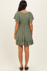 woman wearing an olive green short sleeve tiered dress with a smocked bodice and ruffled hem