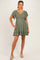 woman wearing a green short sleeve maternity dress with a smocked bodice and ruffled hem, showing her baby bump